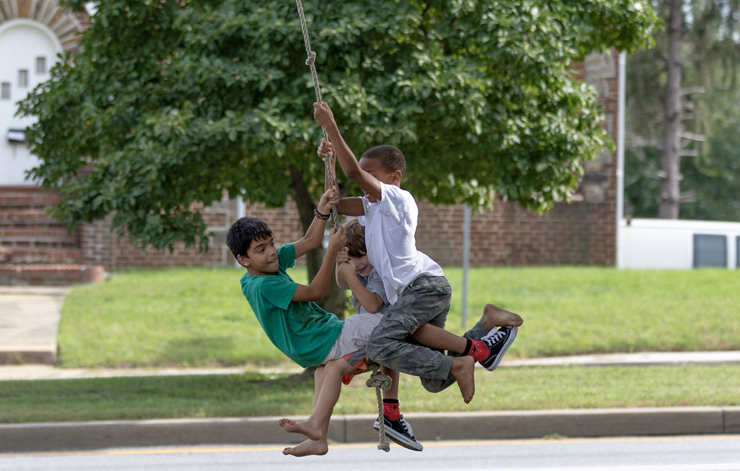 Three students riding a tree swing at the same time