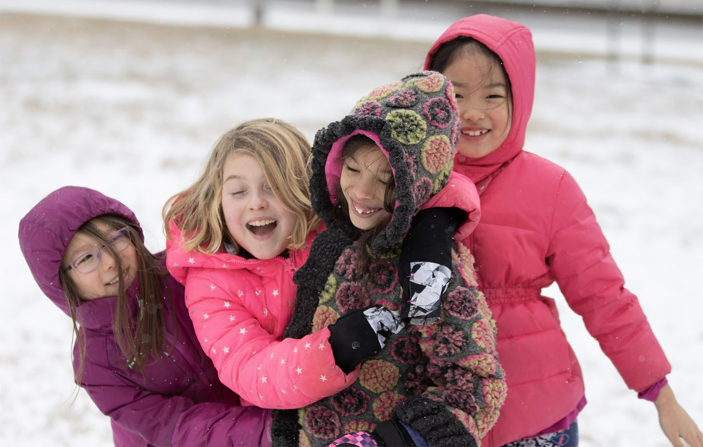 Four girls embracing in the snow